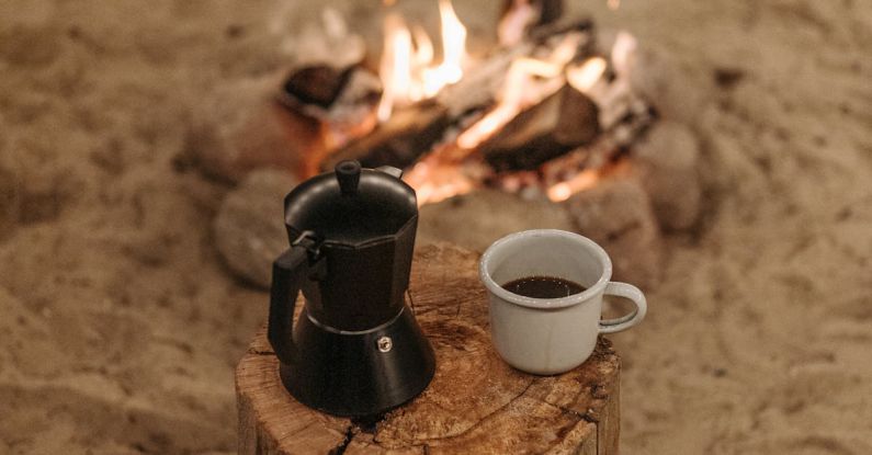 Coffee Maker - A Cup of Coffee on a Wooden Log Near the Bonfire